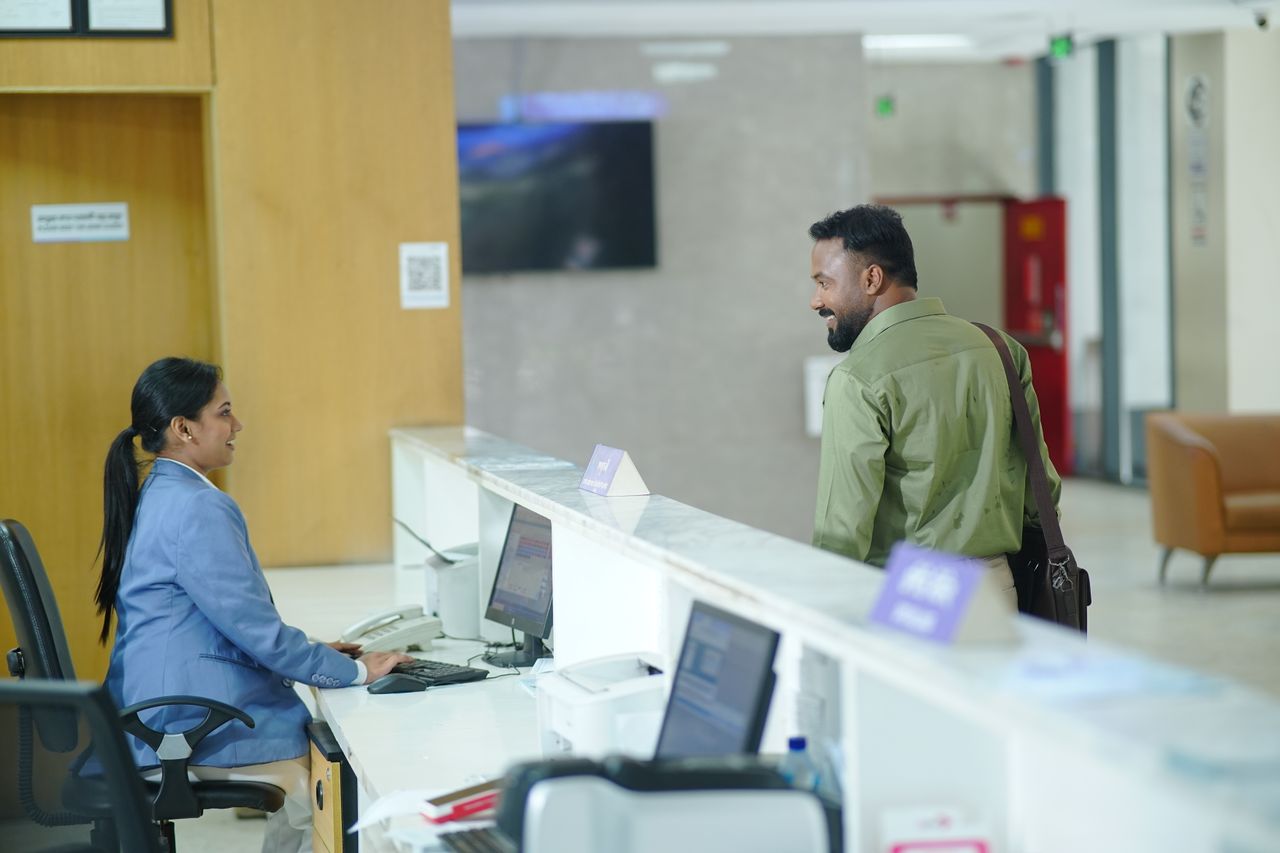 A receptionist assists a guest at the reception desk in a modern hotel lobby in Dhaka, Bangladesh.